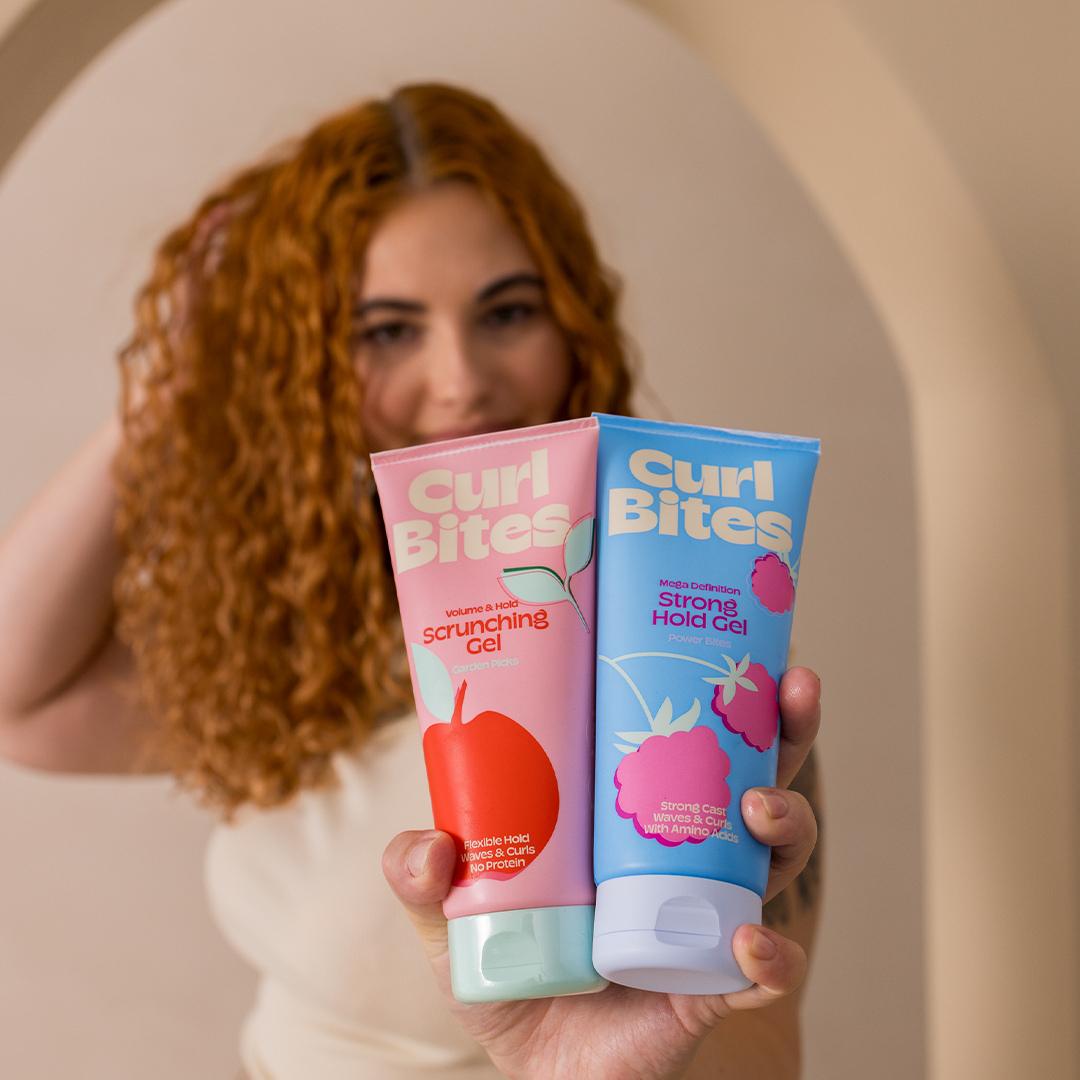Frau mit Locken hält das Curl Bites Scrunching Gel und das Strong Hold Gel in die Kamera