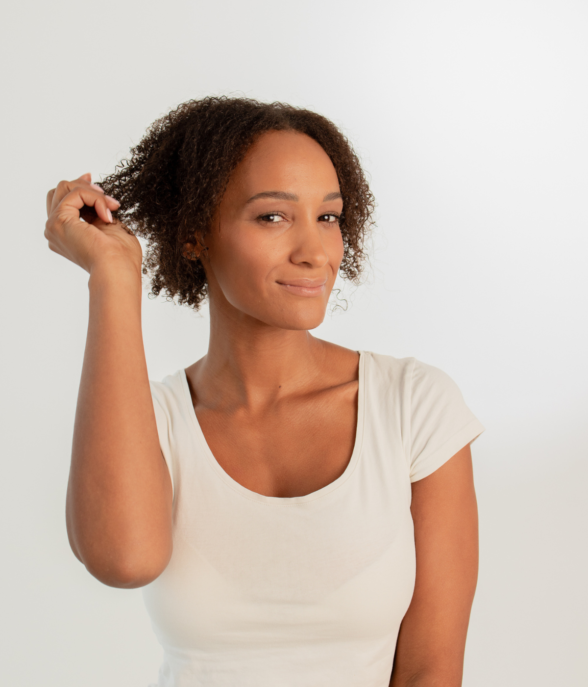 Person mit Afrolocken dreht eine Haarsträhne – führt zu Produktempfehlungen für Afrolocken.