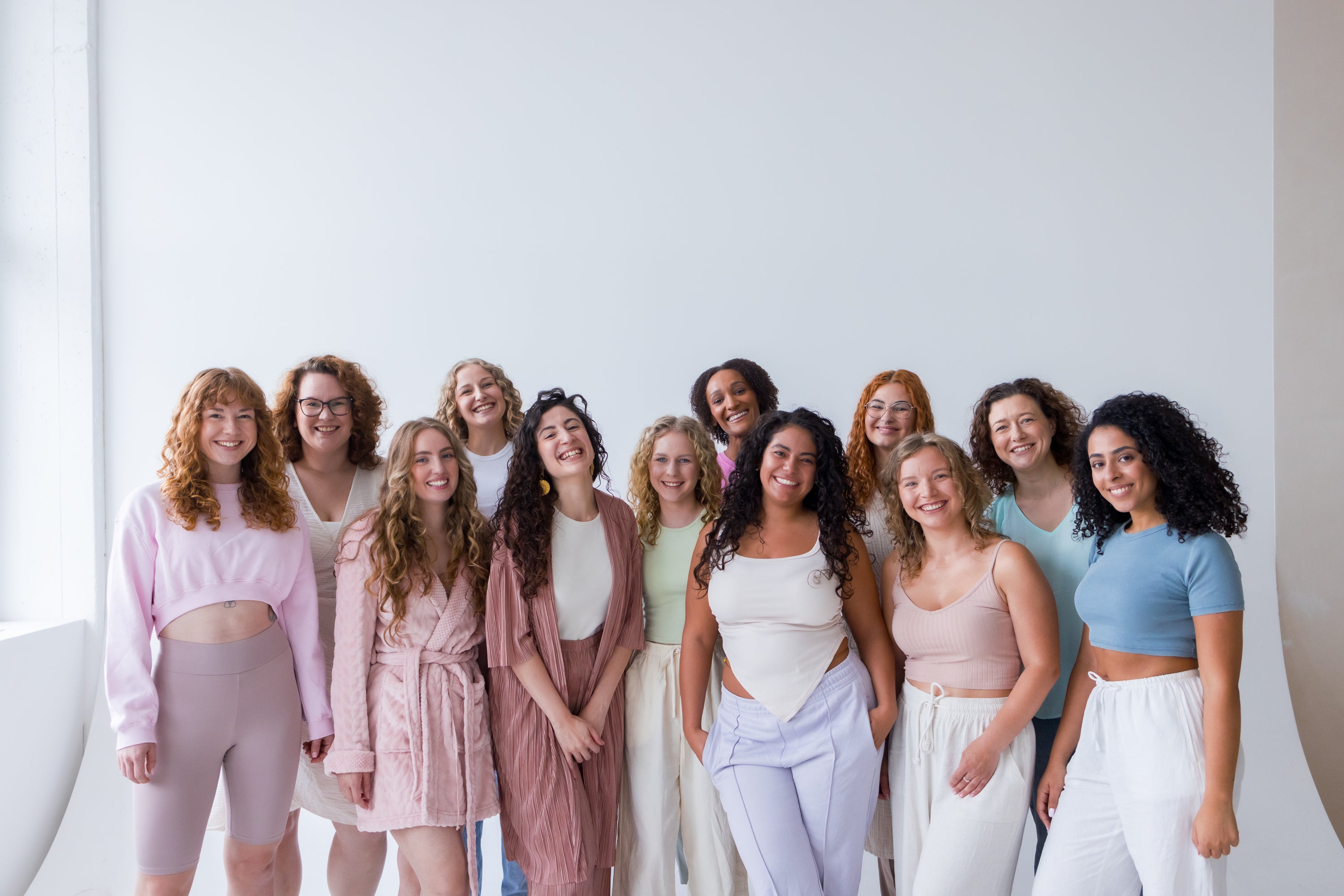 Gruppe von Frauen mit unterschiedlichen Locken- und Wellentypen, die die Vielfalt und den Community-Fokus von Curl Bites repräsentieren