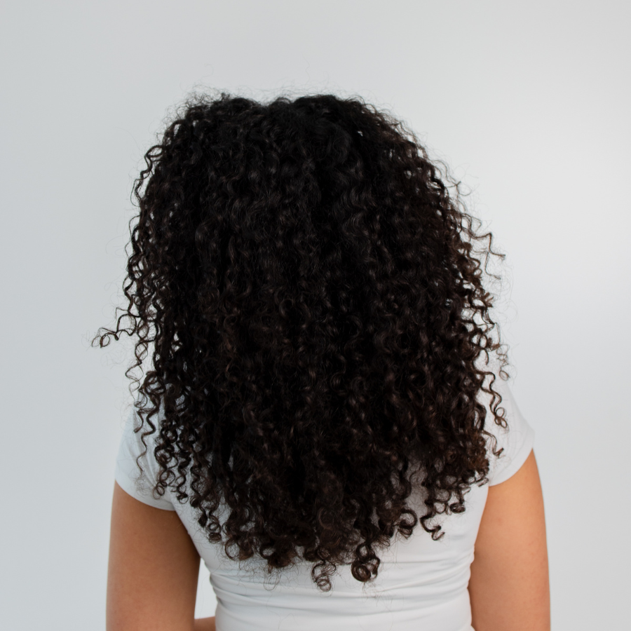 Person mit dichtem, dunklem, lockigem Haar vom Typ 3, von hinten fotografiert