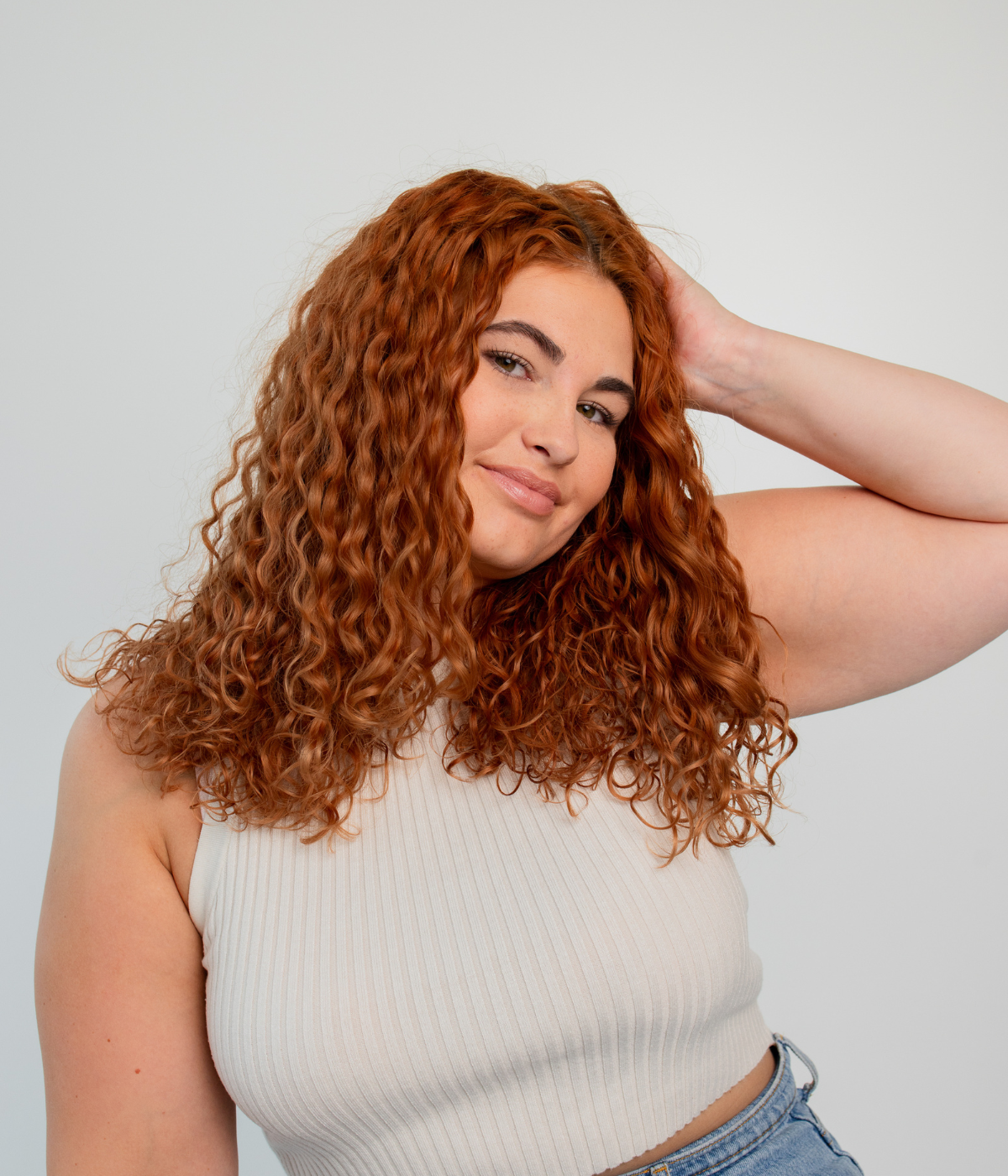 Person mit welligem Haar fasst sich in die Haare – führt zu Produktempfehlungen für wellige Haare.